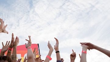 空に向かって手を掲げる若者たちの手