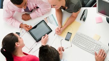 テーブルのドキュメントを囲むスタッフたちのコラボレーション