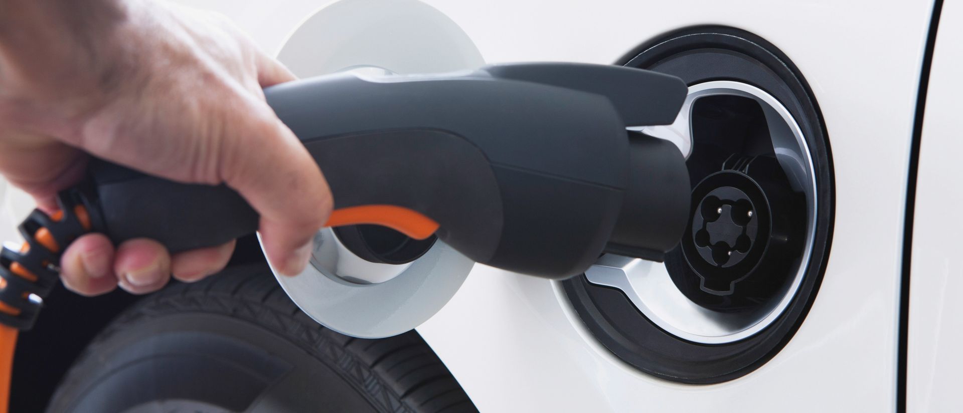 Close up of a male hand plugging in electric car