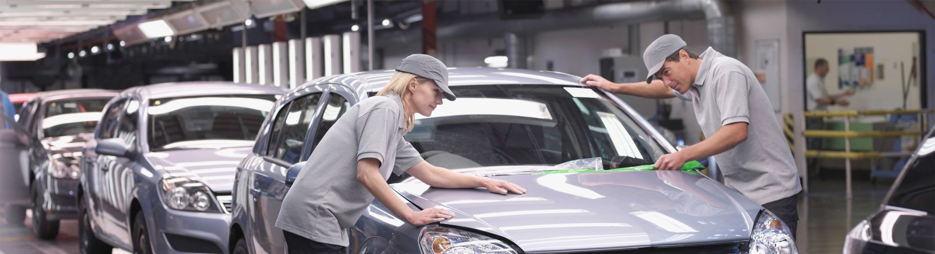 A woman and a man assembling a car in an automotive factory. 