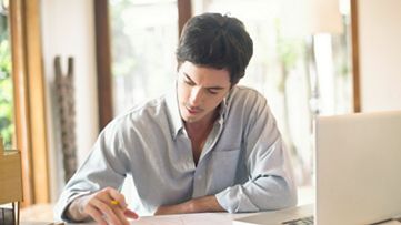 Een persoon die aan documenten werkt achter een laptop, met low-code/no-code