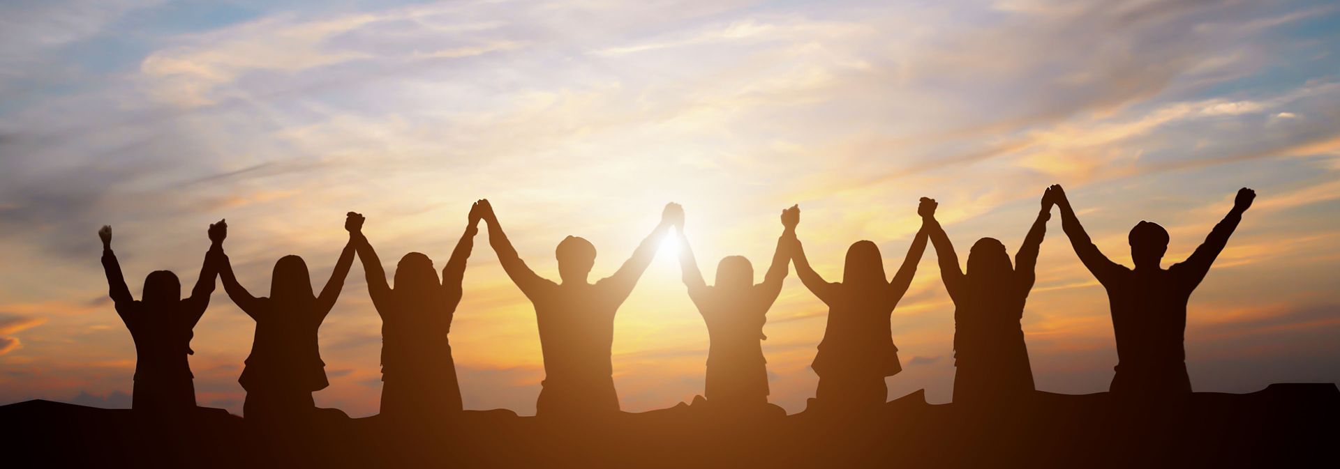 图片:日出时分,一群人在户外手牵手举向空中