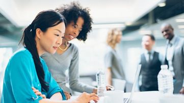 Two women reviewing information on a laptop screen