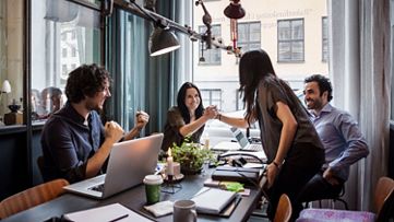 Happy businesswomen holding hands in meeting at creative office