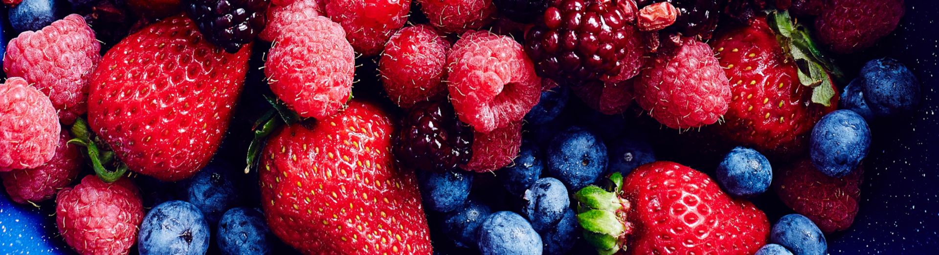 Bild einer Auslage in einem Lebensmittelgeschäft mit einer Fülle an Erdbeeren, Brombeeren, Blaubeeren, Himbeeren und Preiselbeeren