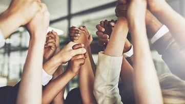 Viele Hände, die sich über dem Kopf festhalten