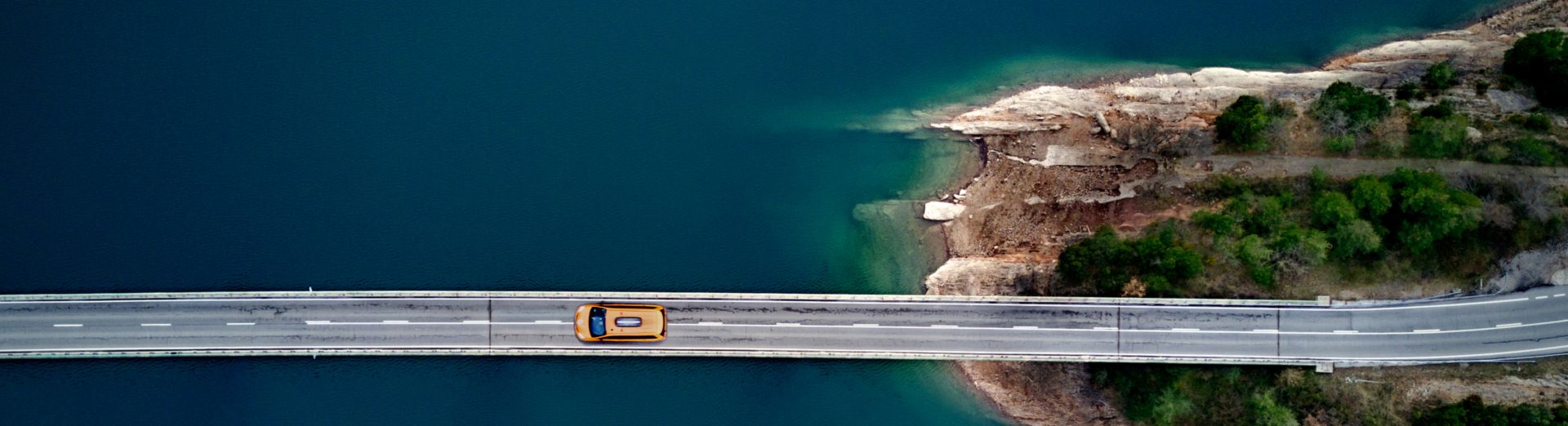 Car driving on bridge across blue water