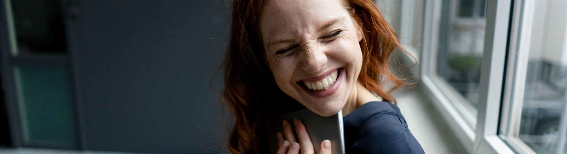 Portrait of laughing redheaded businesswoman with digital tablet in a loft