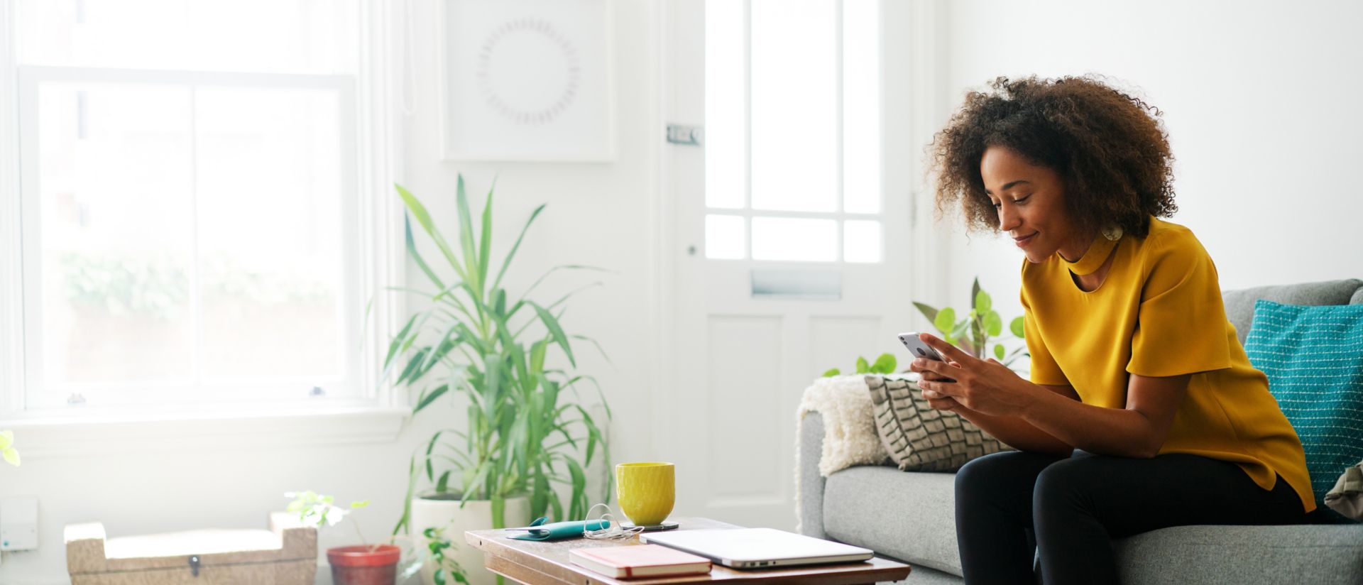  Imagen de una mujer sentada en un sofá usando un teléfono inteligente para ver software de contabilidad para pequeñas empresas