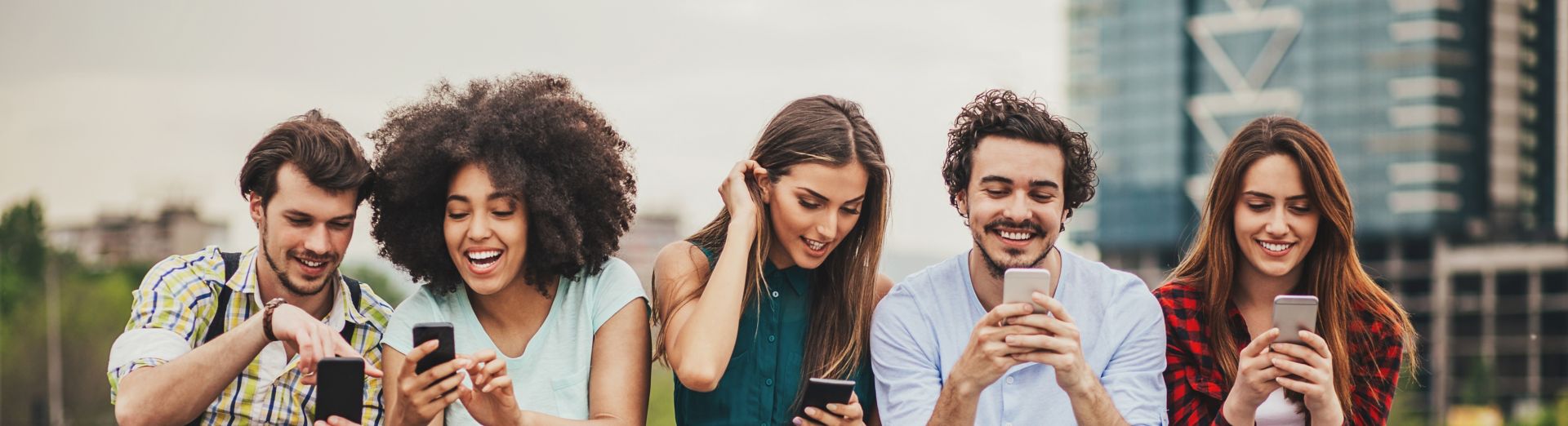 Five young friends looking at their cell phones