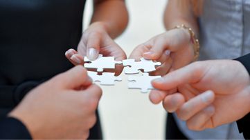 four people holding puzzle pieces