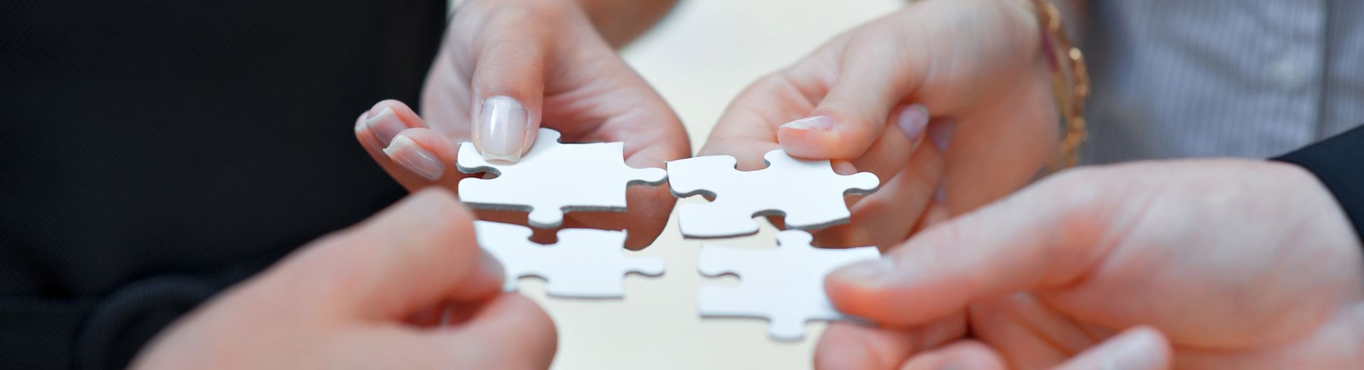 Imagem de quatro mãos com peças de quebra-cabeças representando o SAP Supply Chain Management