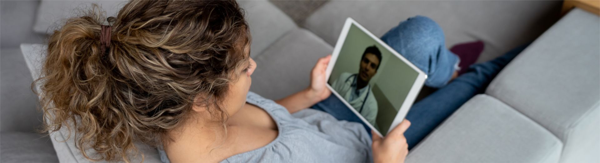 Woman at home talking with her doctor on tablet; telehealth appointment