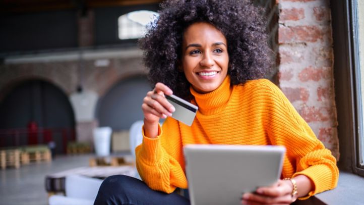 Woman holding the card in one hand tablet device in other hand