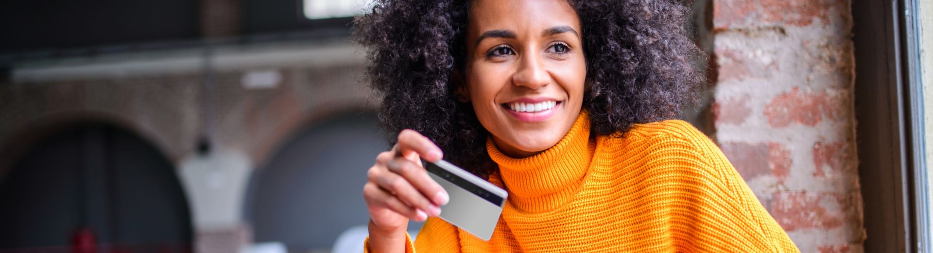 Smiling woman holds up a tablet and a credit card to make a purchase.
