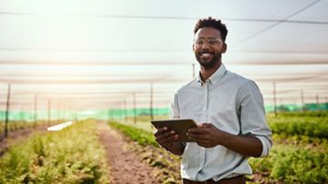 A man holding a tablet in front of a field