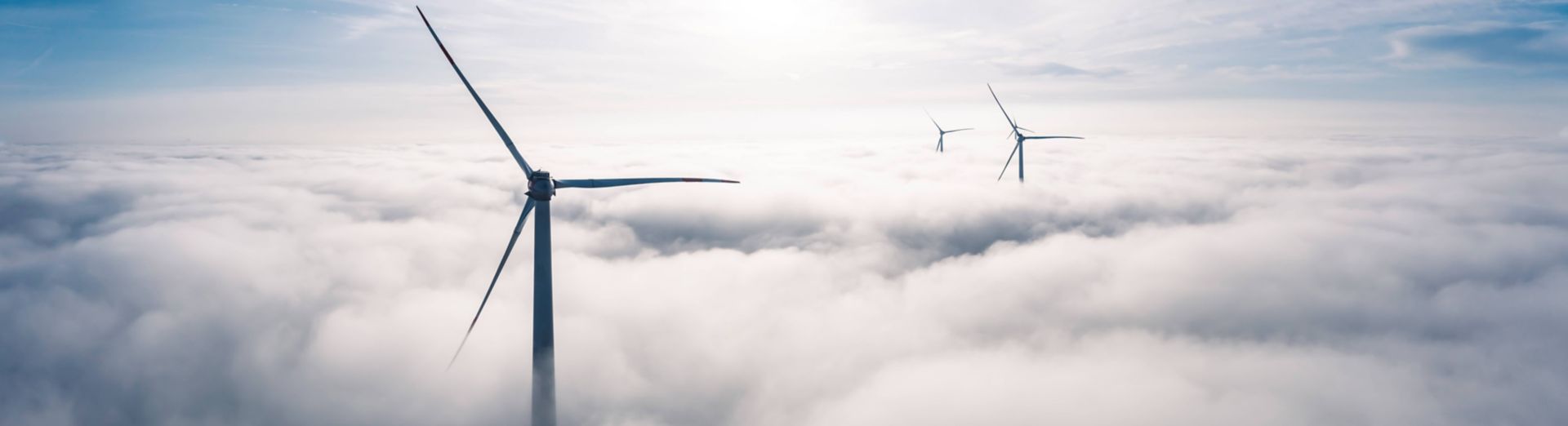 Aerial view of wind turbines shrouded in clouds at sunrise