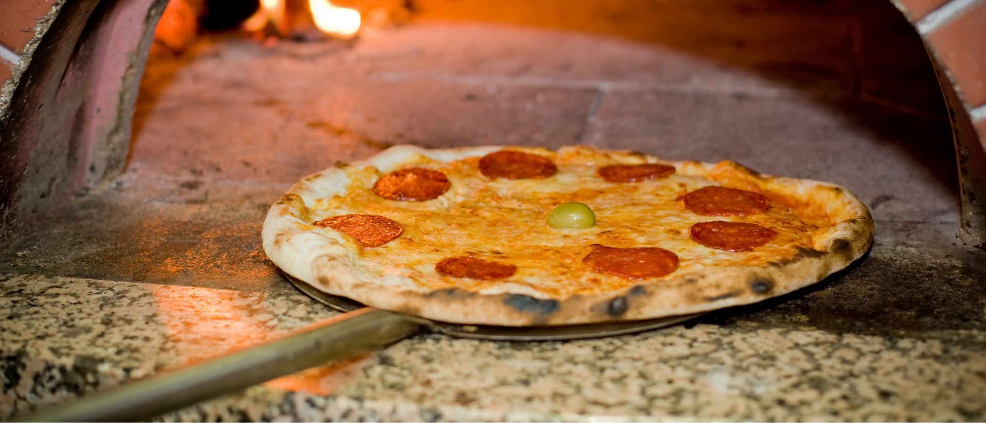 Image of pizza being taken out of the oven