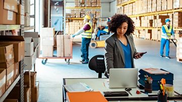 倉庫中使用筆記型電腦工作的商務女性