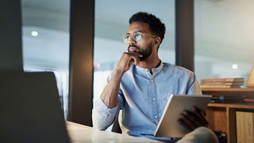 man holding tablet looking at computer
