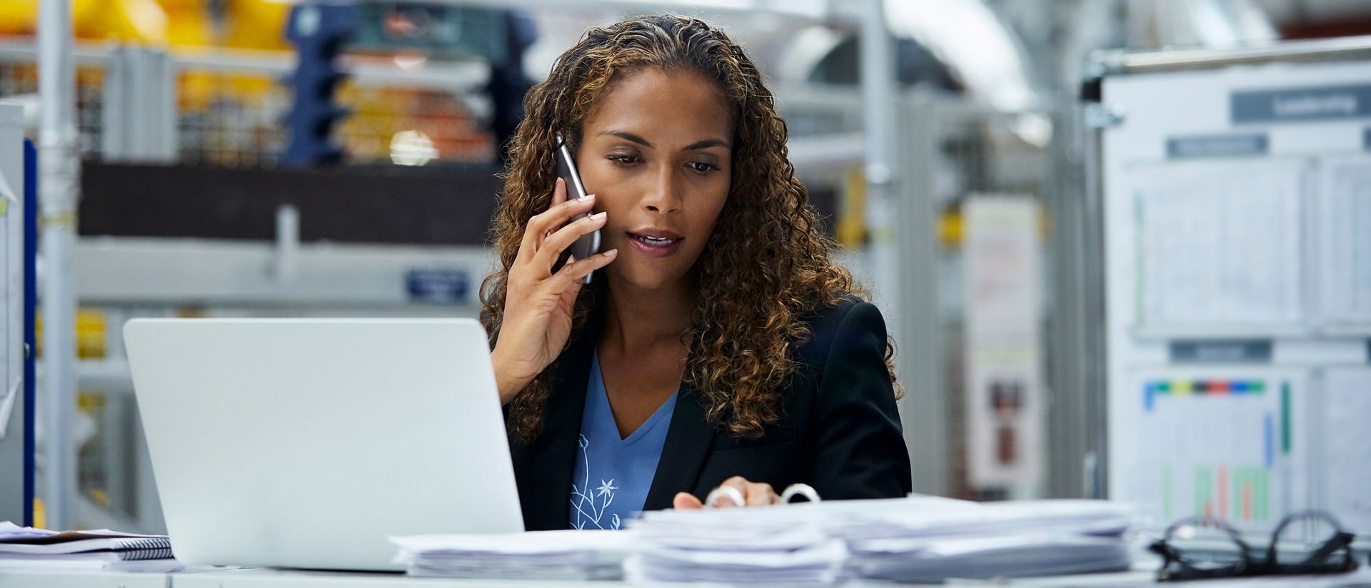 Young businesswoman using technologies at desk in automotive factory