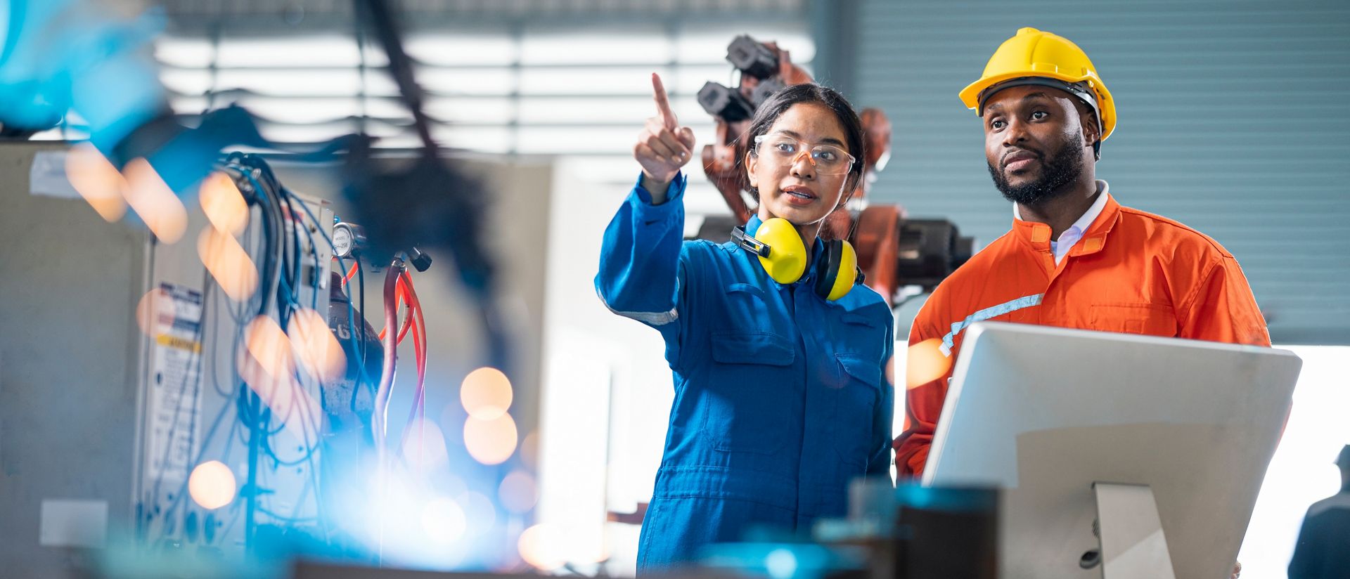 Female engineer presentation robotic welding process to her team in testing area of research and development.