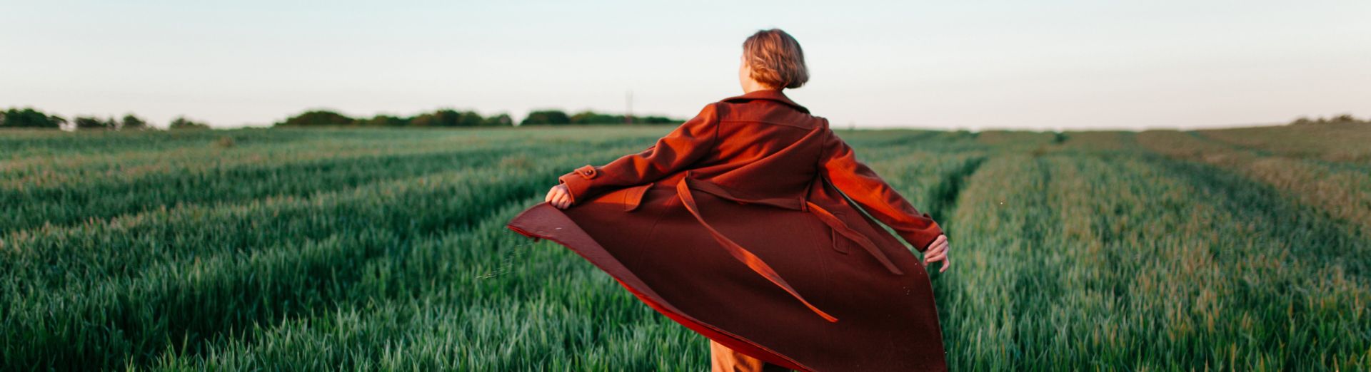 Woman runs through field in a vibrant red coat.