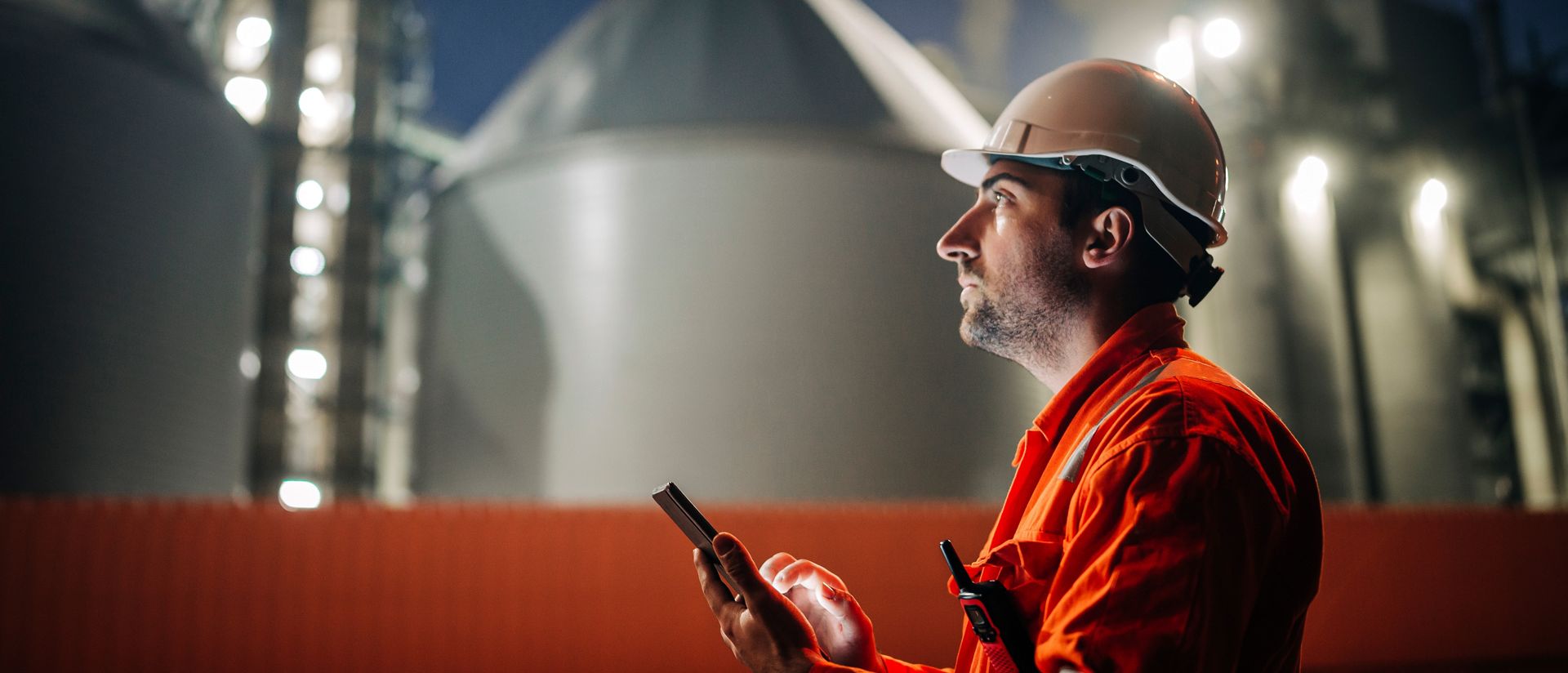 Engineer using tablet at petroleum industrial factory at night 