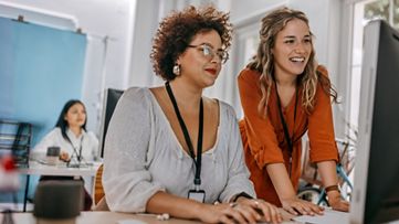 Two business colleagues working together on desktop computer at office