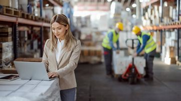  도매 유통 회사에서 노트북으로 작업 중인 창고 관리자