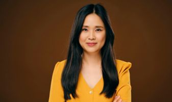 Frau in gelbem Kleid steht mit verschränkten Armen.