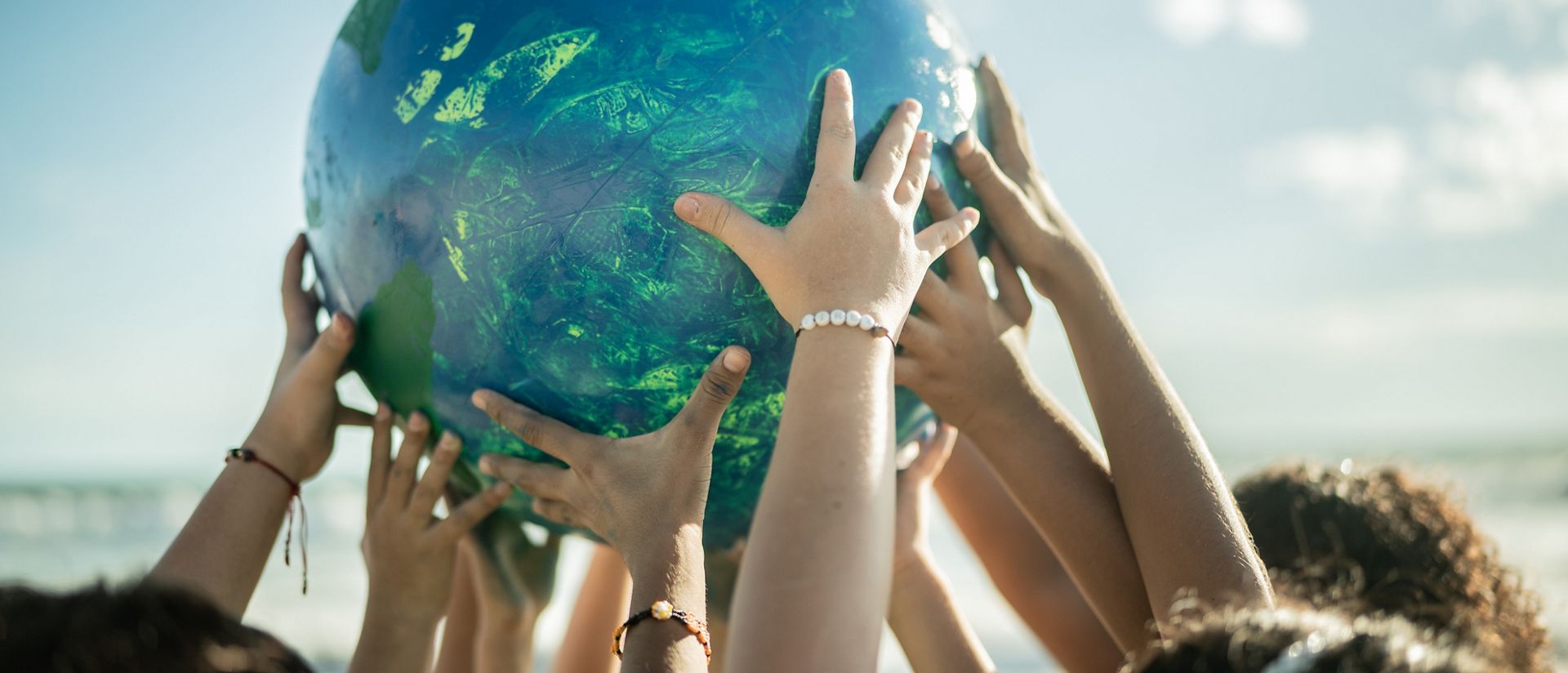 Close-up of children holding a planet at the beach