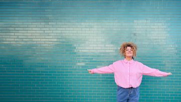 Woman in pink shirt with her arms stretched out to each side