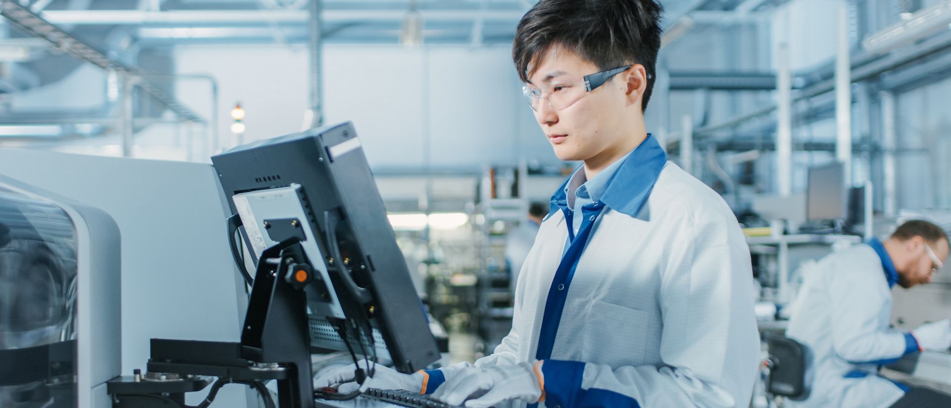 Engineer using a computer to program electronic machinery for a circuit board assembly line