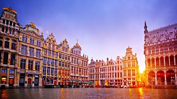Historic Grand Place in Brussels at sunset with ornate buildings and glowing sky over cobblestone square