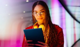 Frau betrachtet ein Tablet vor einem futuristischen Hintergrund.