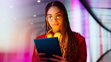 Junge Frau mit Tablet in der Hand informiert sich über das Thema Business AI