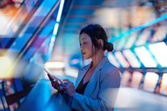 Young business woman holding smartphone with a computer generated background. Innovation, metaverse and futuristic concepts.