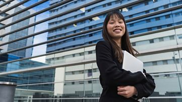 Businesswoman in front of a large glass-fronted business building