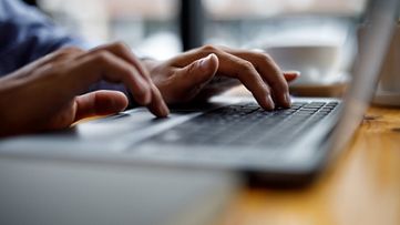 Hands typing on laptop