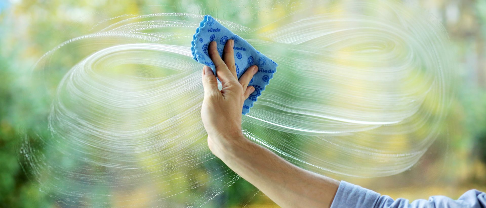 Imagen de una mujer usando un paño para limpiar una ventana